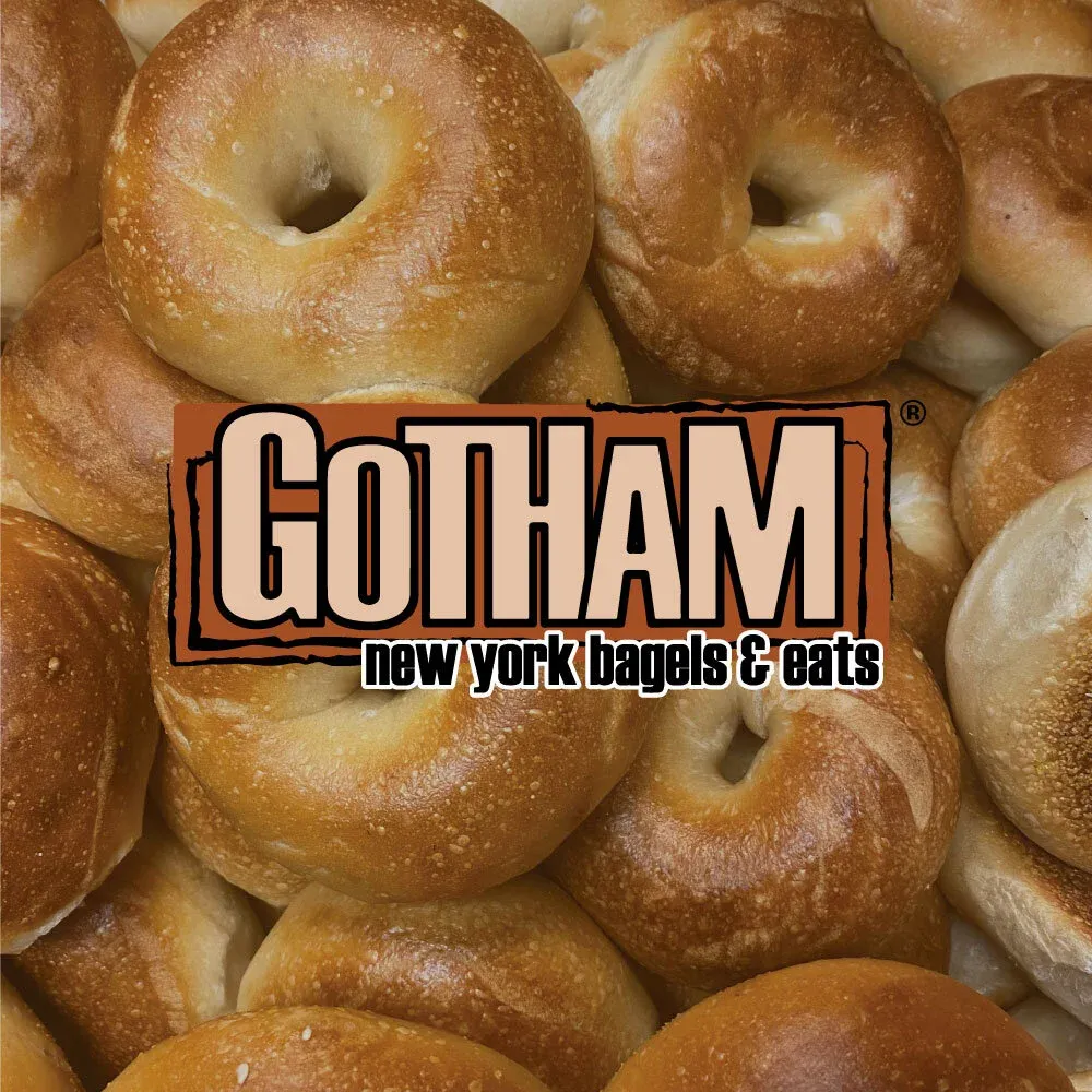 A close-up pile of golden, hand-rolled Gotham Bagels fresh from the oven.